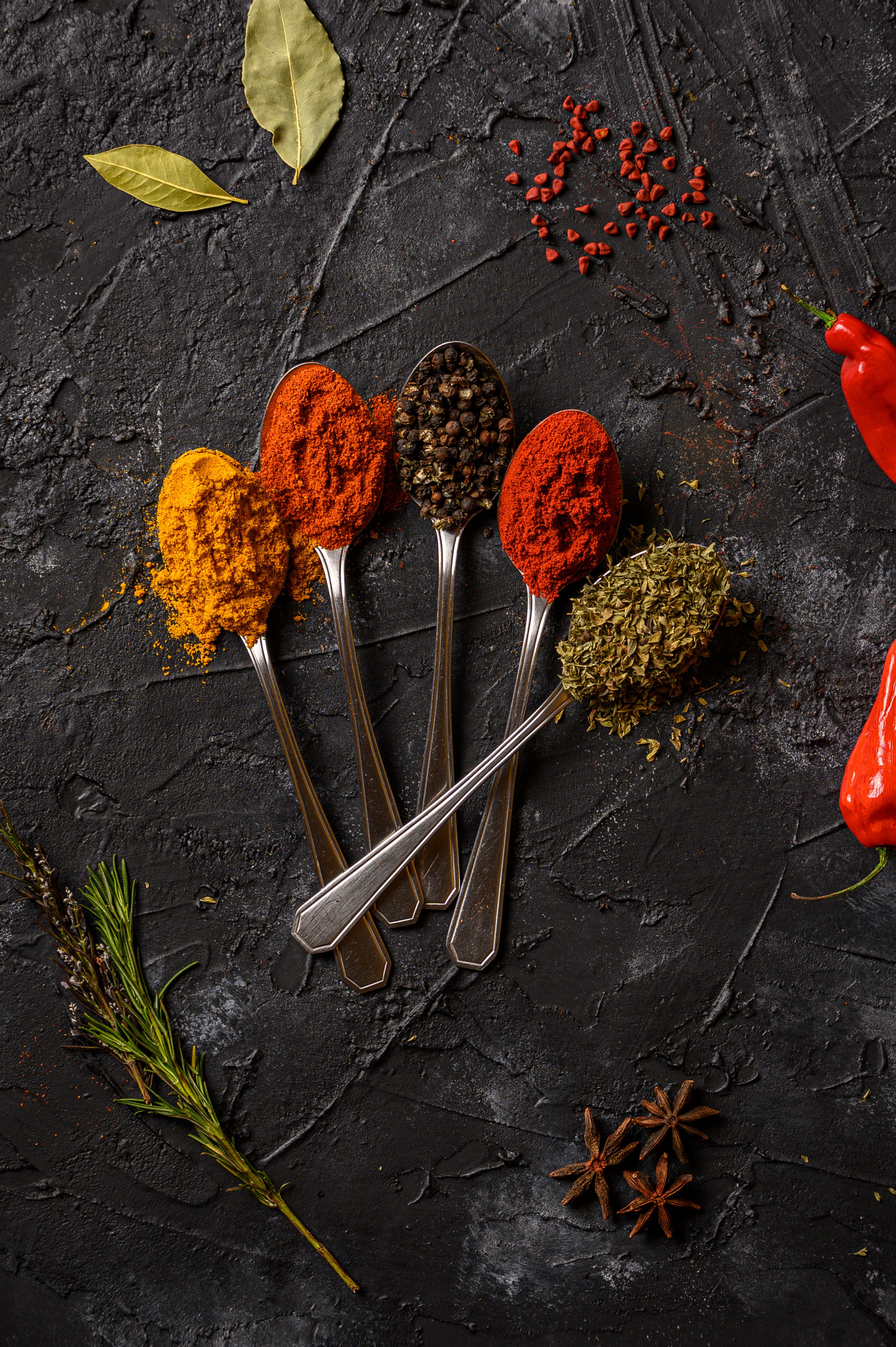 Whole spices arranged on spoons against a premium dark background